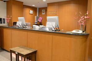 Ein Empfangstresen mit zwei Computermonitoren, einem Telefon und einem kleinen Tisch.