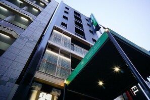 Un hôtel doté d’une façade moderne, de nombreux balcons et d’une enseigne verte indiquant son nom.