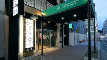 A hotel entrance with a green awning, a signboard, and a glass door.