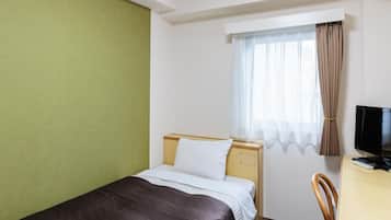 A hotel room with a single bed, a desk with a television, and a window with curtains.