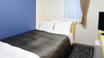 A hotel room with a bed, a television, a window with curtains, and a desk.