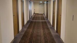 Ein Hotelkorridor mit Teppichböden, Türen mit den Nummern 1112 und 1113 sowie einem Feuerlöscher an der Wand.