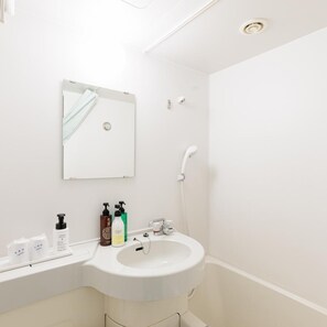 A modern bathroom with a white sink, mirror, and shower.