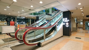 Eine Rolltreppe in einem Einkaufszentrum, ausgestattet mit Glasschilden und einer digitalen Anzeige.