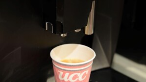 Een koffieapparaat schenkt koffie in een beker met branding.