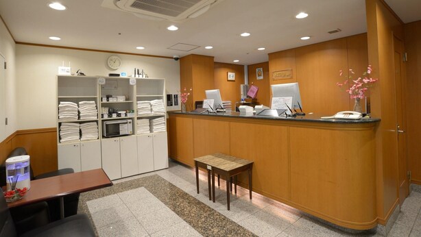 A reception area with a counter, computer, and a small table. - Nagoya Sakae Green Hotel (Nagoya)