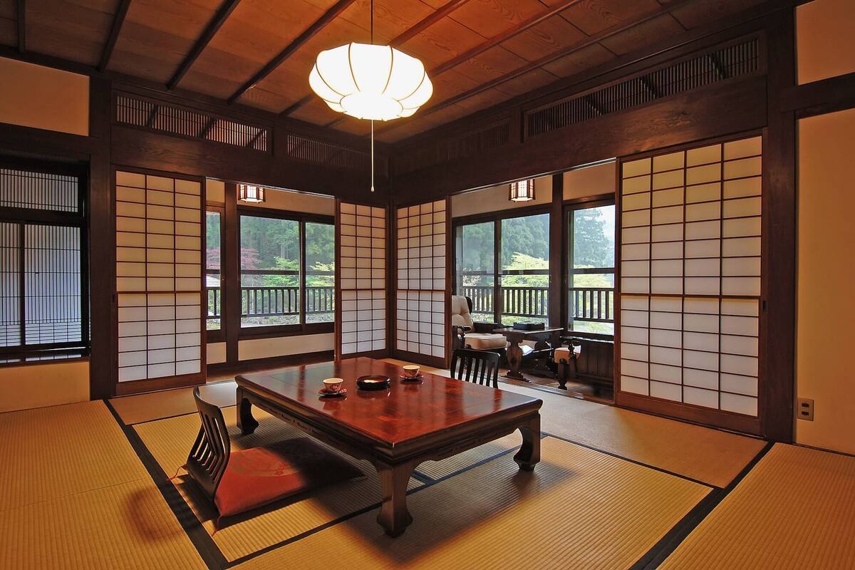 A traditional Japanese room with tatami flooring, a low wooden table, and sliding doors.