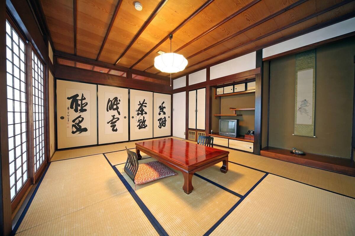 A traditional Japanese room with tatami flooring, a wooden table, and calligraphy on the walls.