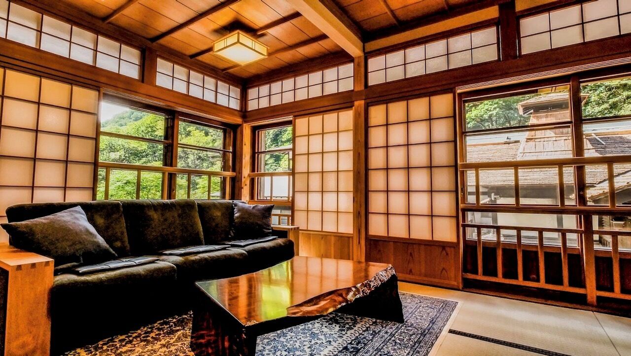 Una habitación tradicional japonesa con suelo de tatami, una mesa de madera baja y un sofá.