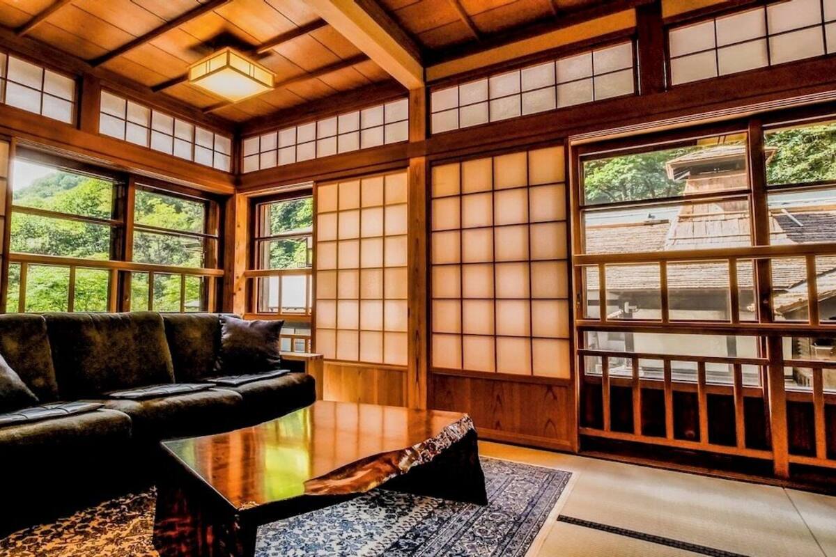 A traditional Japanese-style room with tatami flooring, a low wooden table, and a sofa.