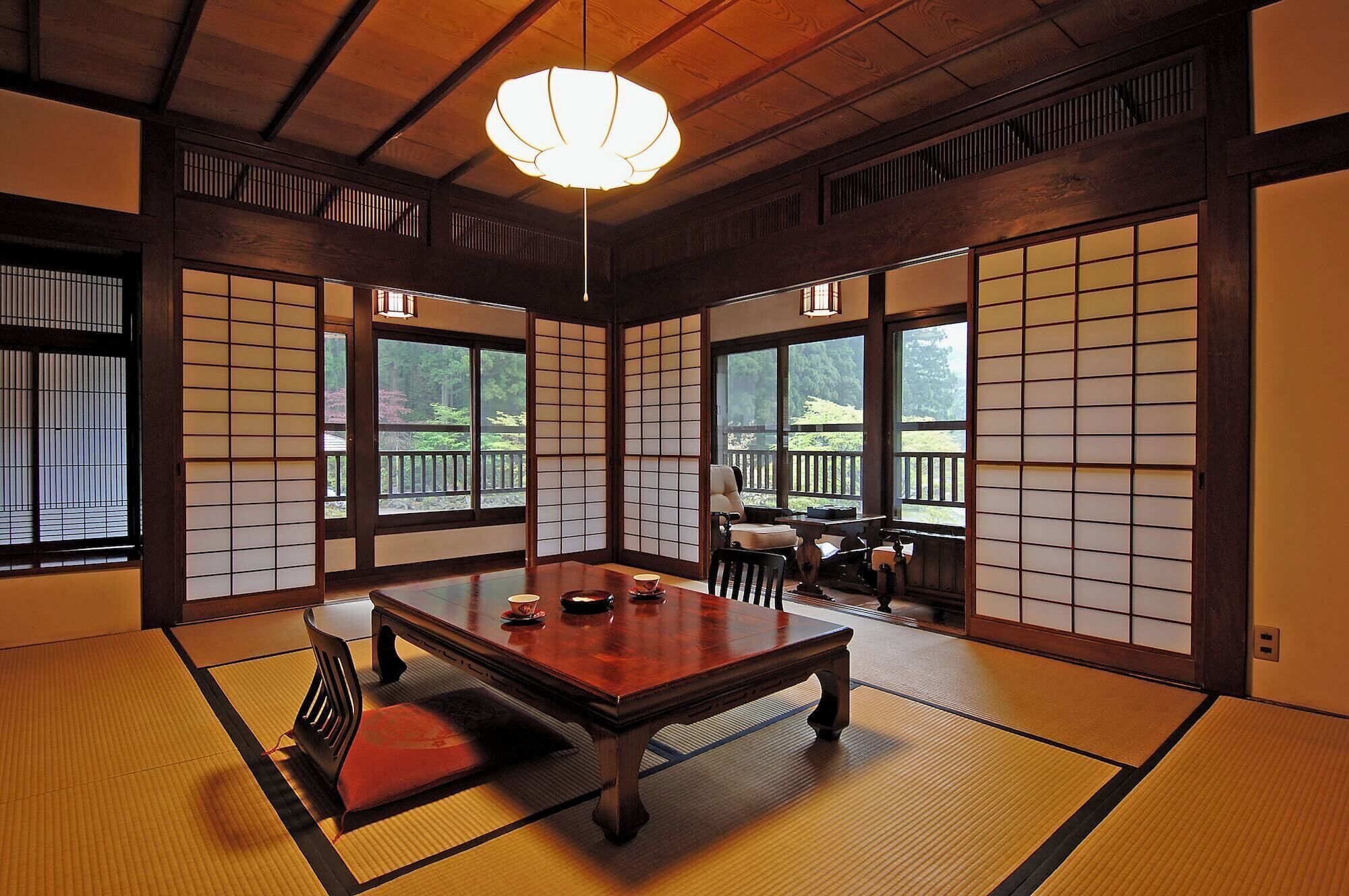 Una habitación tradicional japonesa con suelo de tatami, una mesa baja de madera y puertas correderas shoji.