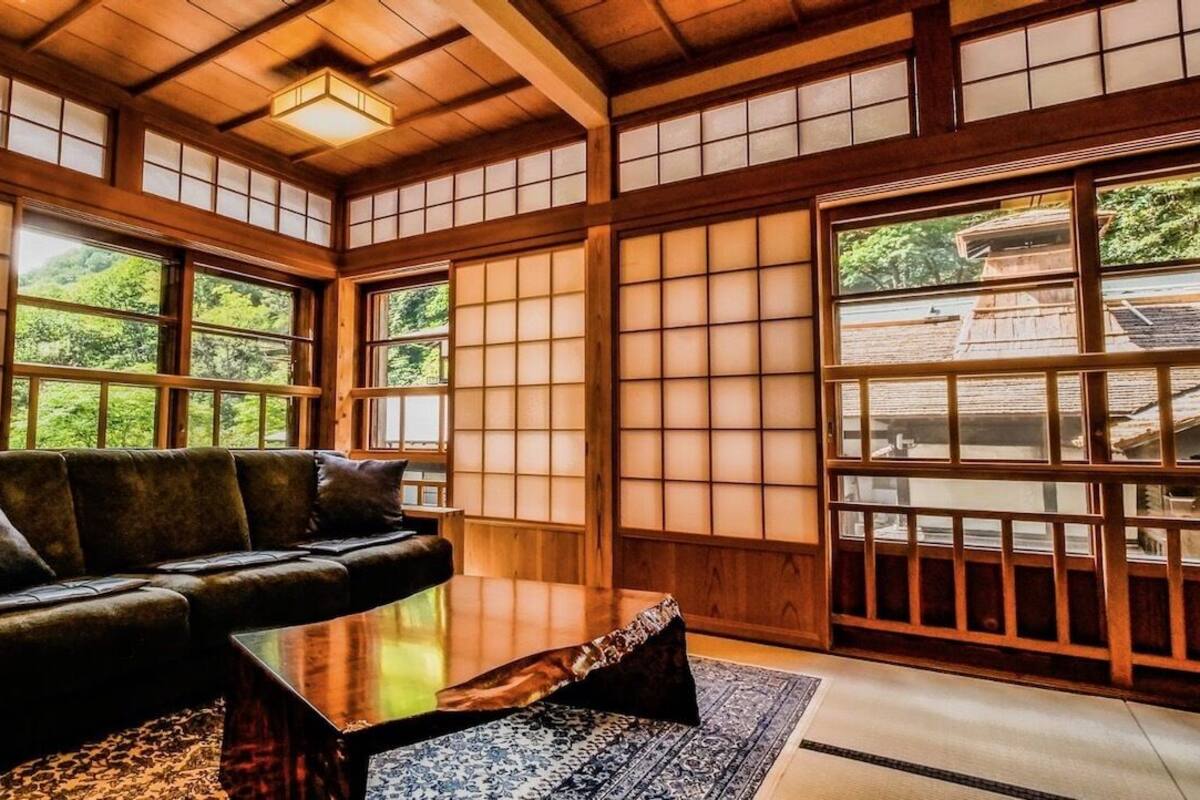 A traditional Japanese room with tatami flooring, a low wooden table, a sofa, and large shoji screens.