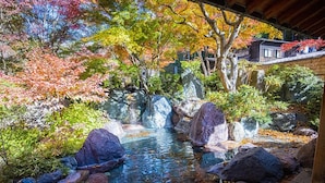 Un jardín con un estanque, rocas y follaje otoñal.