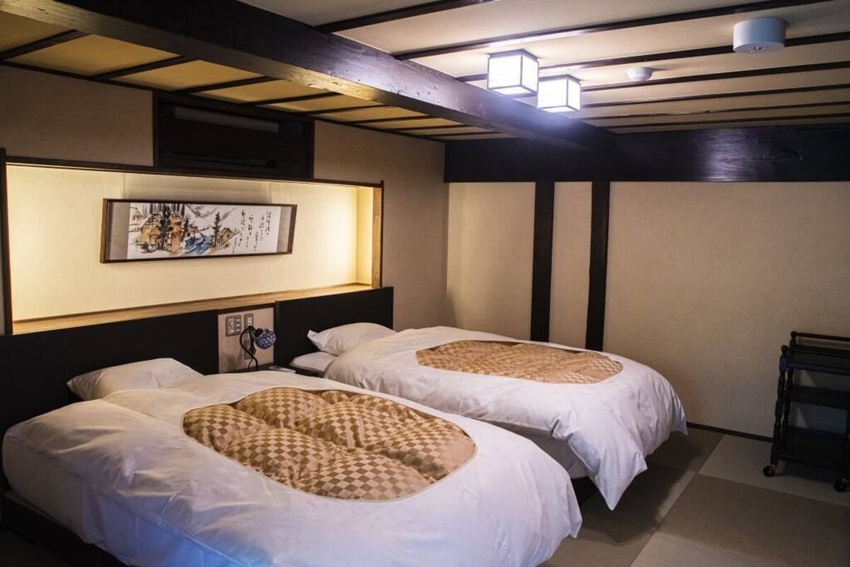 A hotel room with two beds, a wall-mounted artwork, and a ceiling light fixture.