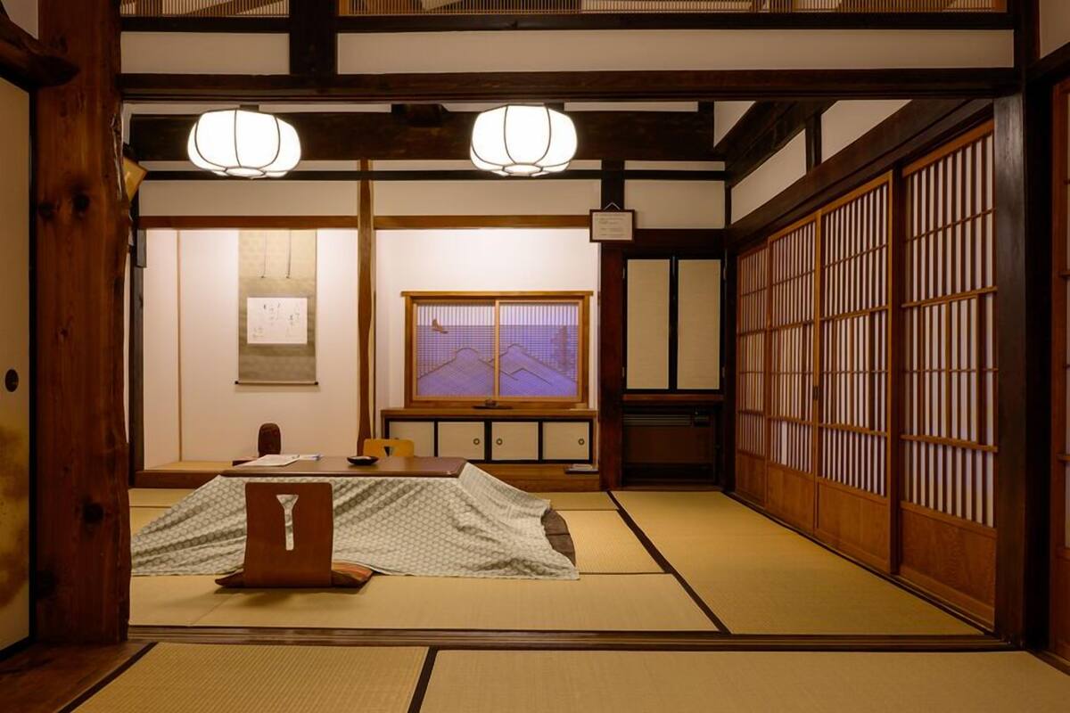 A traditional Japanese room with tatami flooring, sliding doors, and a low table with a cushion.