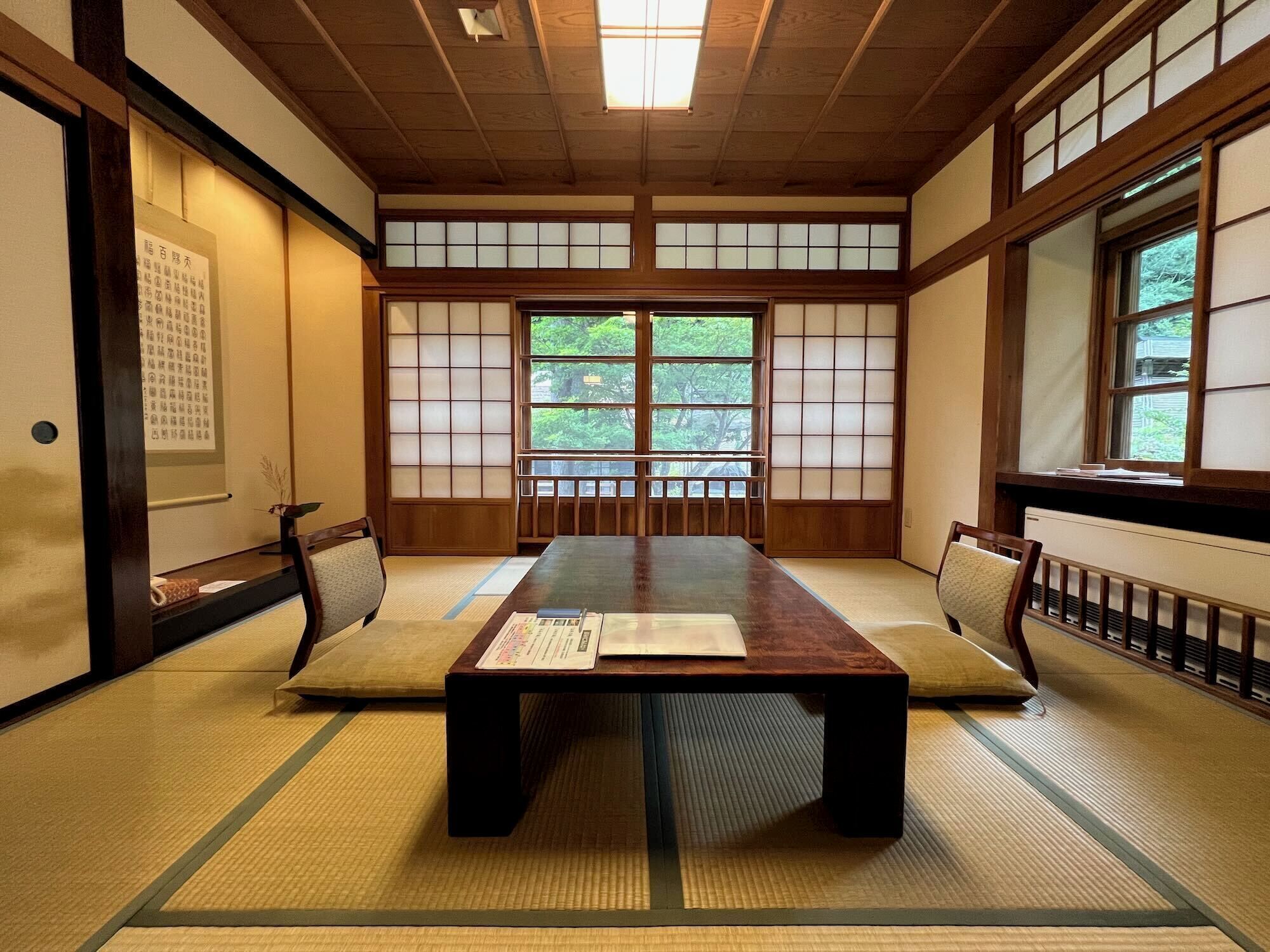 Una habitación japonesa tradicional con suelo de tatami, una mesa baja y puertas correderas.