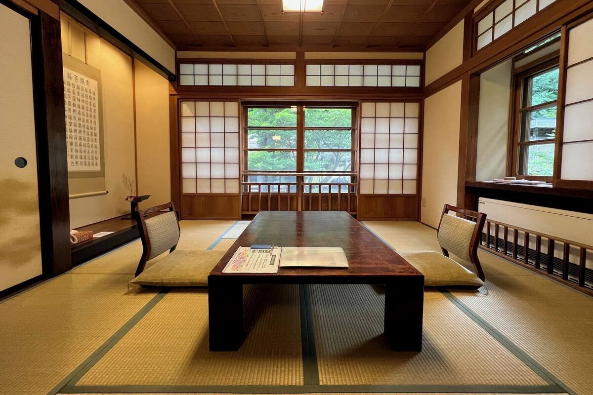 A traditional Japanese room with tatami flooring, a low table, and sliding doors.