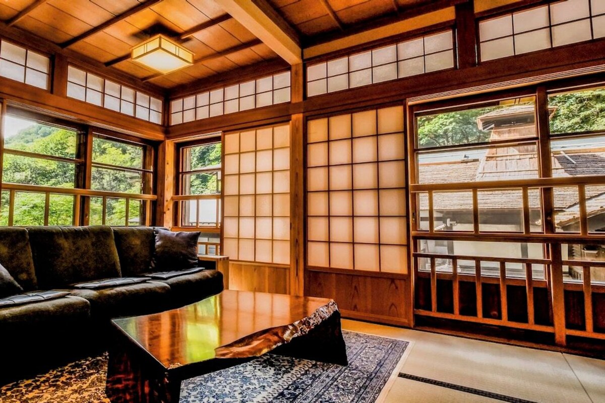 Una habitación tradicional japonesa con suelo de tatami, una mesa de madera baja y un sofá.