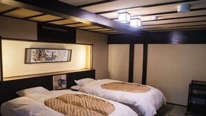 Ein Hotelzimmer mit zwei Betten, einem Wandbild und einer Deckenleuchte.