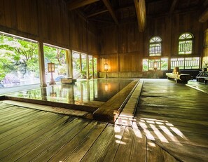 Un bain traditionnel en bois, doté d’une grande piscine intérieure, de planchers en bois et de grandes fenêtres laissant entrer la lumière naturelle.