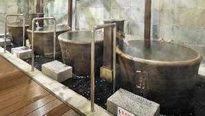 Ein traditionelles japanisches Onsen mit mehreren Thermalbecken und Steinwänden.