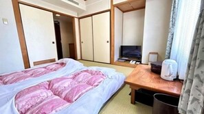 A hotel room with a bed, a television, a coffee maker, and a wooden desk. - Sky Hotel (Matsuyama)