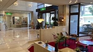 Eine Hotelhalle mit Empfangsschalter, Sitzgelegenheiten und großen Fenstern.