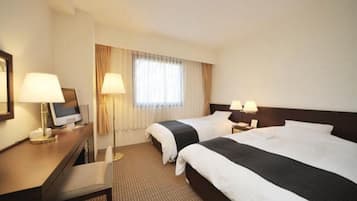 A hotel room with two beds, a desk with a computer, and a lamp.