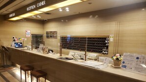 A reception area with a counter, chairs, and a wall displaying various items. - Hotel Castle Plaza (Akashi)