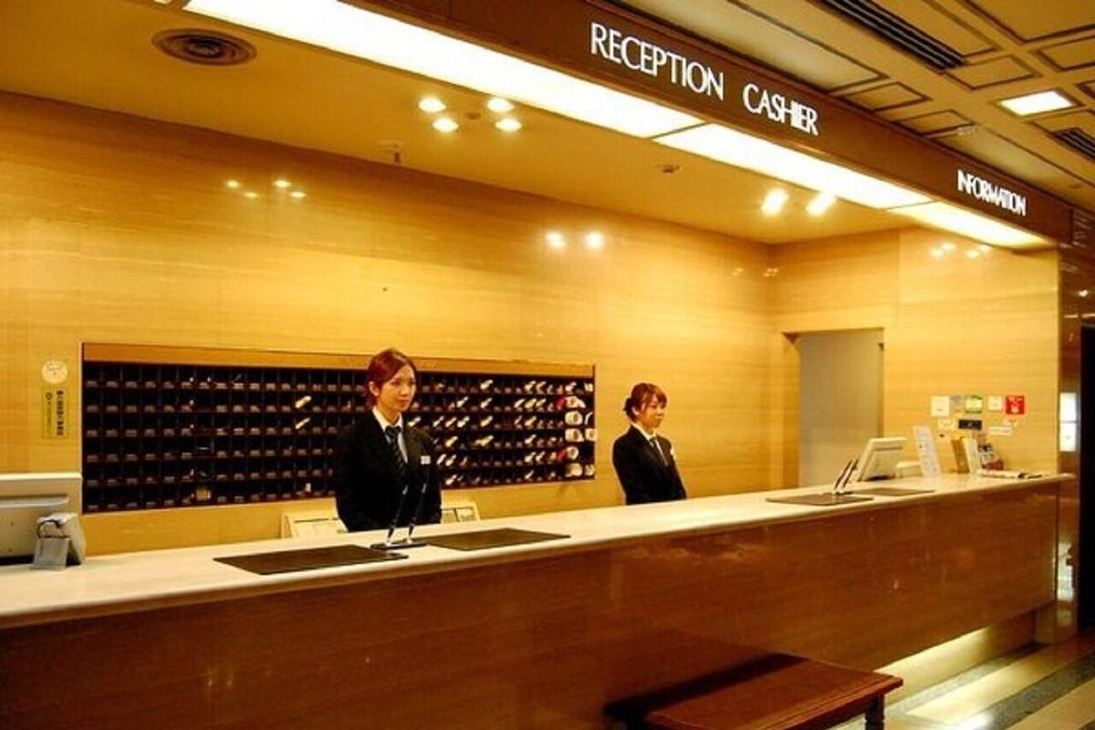 A reception area with a counter, two staff members, and a shoe display.