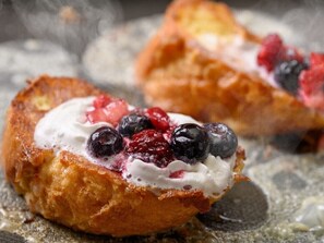 Un postre con crema batida y frutos rojos.