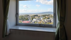 A window with a view of a cityscape, curtains, and a handle.