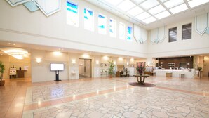 A spacious lobby with a high ceiling, large windows, and a central reception desk.