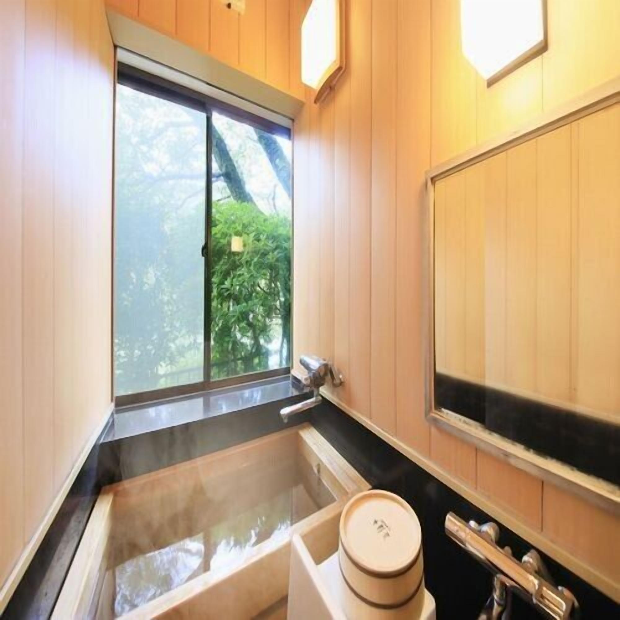 A bathroom with a bathtub, a window, and wooden walls.