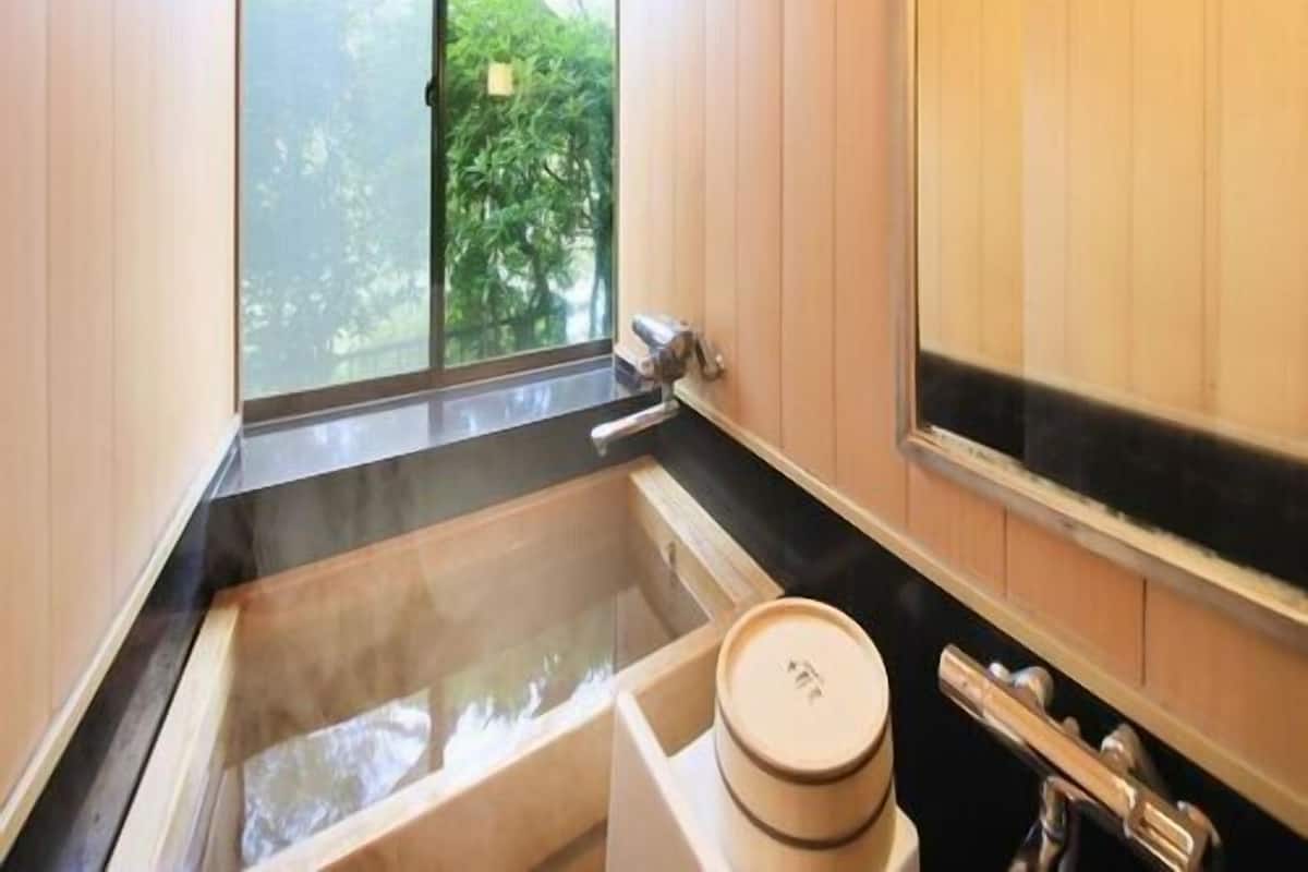 A bathroom with a bathtub, a window, and wooden walls.