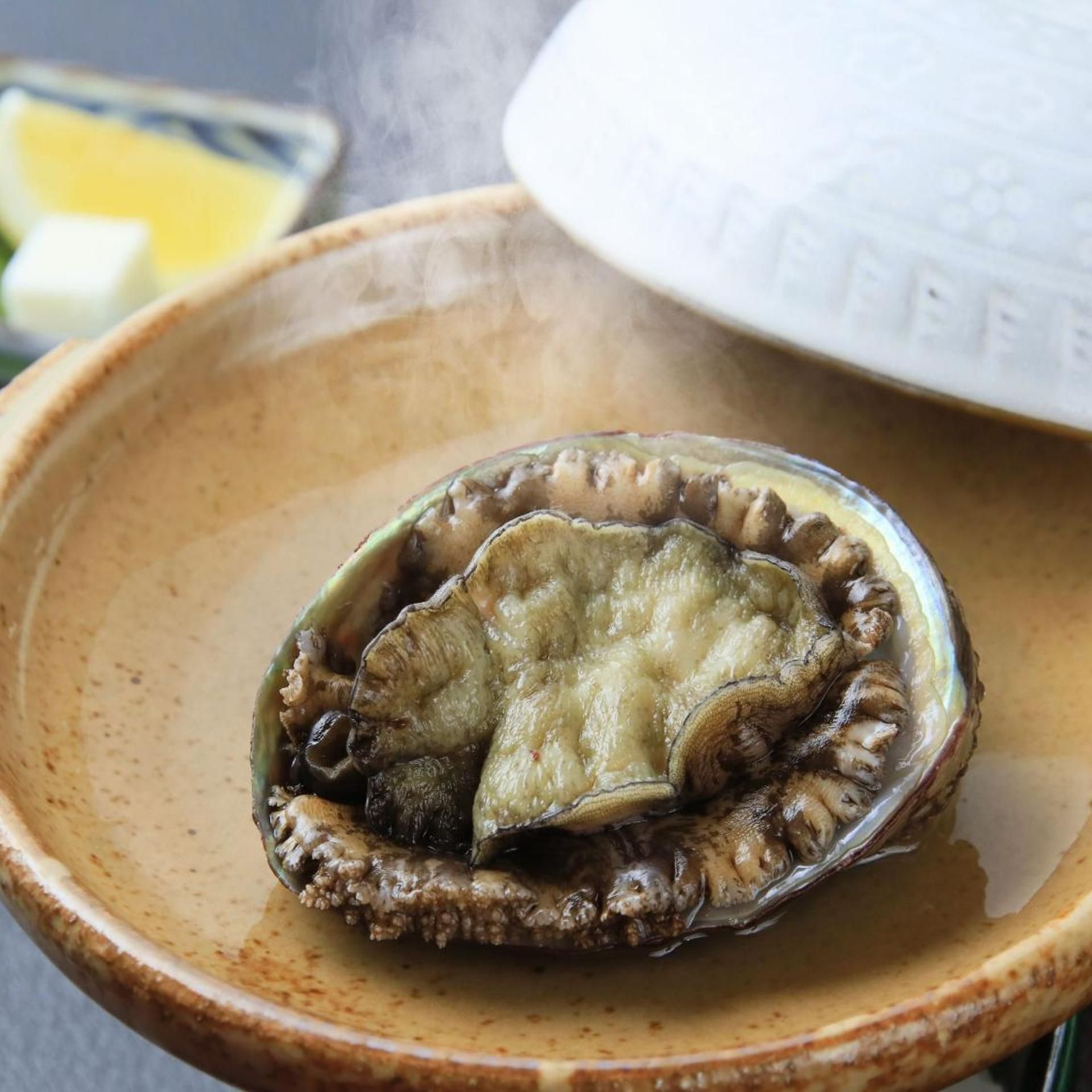 A ceramic bowl containing a shell with a scallop inside.