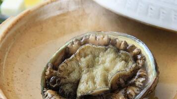 A ceramic bowl containing a shell with a scallop inside.