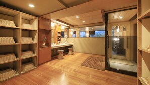Un baño con piso de madera, un lavamanos, un espejo y cestos de mimbre en estantes.