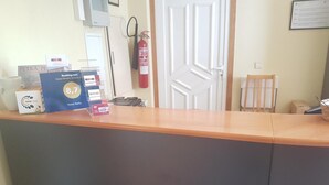 Ein Hotelrezeptionstresen mit Schild für eine Gästeauszeichnung, einem Feuerlöscher und einer Tür im Hintergrund.