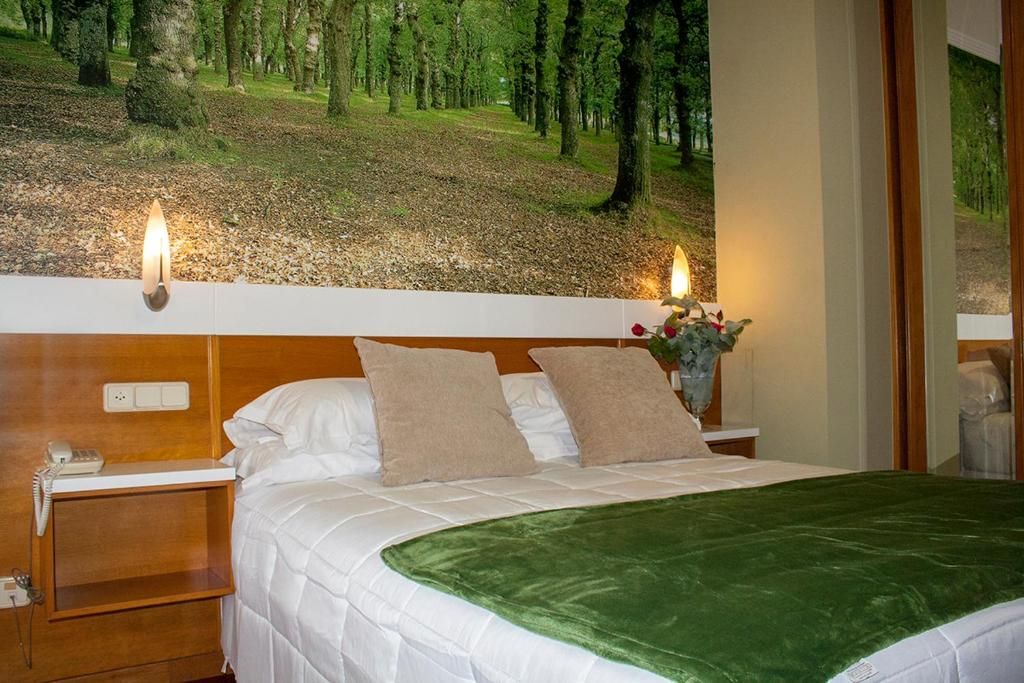 A hotel room with a bed, a nightstand, a telephone, and a wall-mounted lamp.