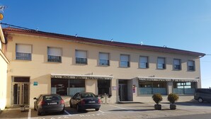 Ein zweistöckiges Gebäude mit einem Restaurant im Erdgeschoss und einem Hotel im Obergeschoss. Vor dem Haus befinden sich zwei Autos.