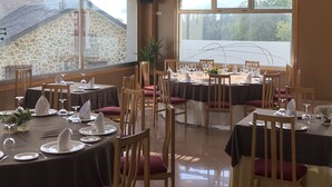 Ein Restaurant mit runden Tischen, großen Fenstern mit Ausblick und einer Steinsäule im Hintergrund.