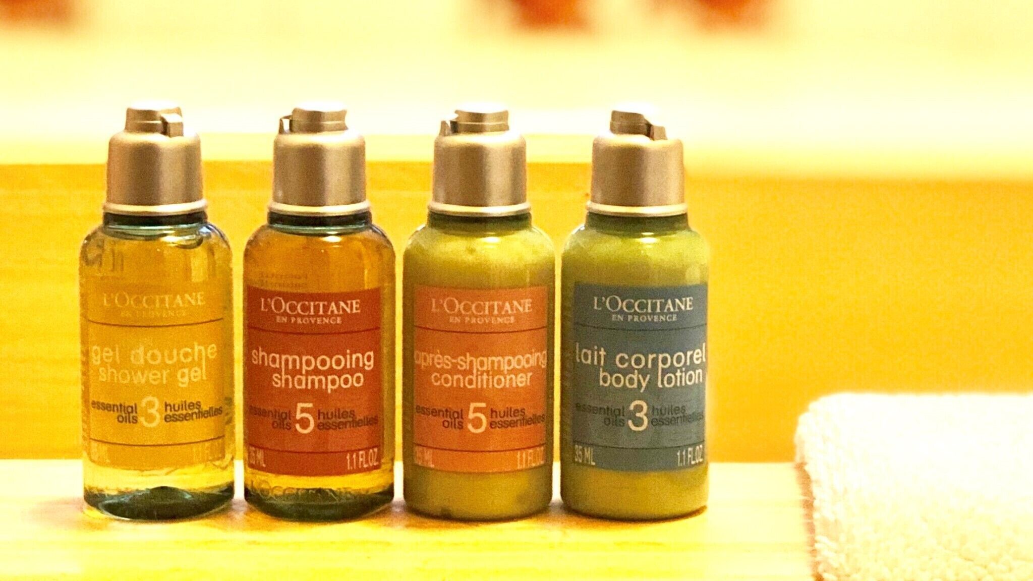 Cuatro botellas de productos L'OCCITANE sobre una estantería.