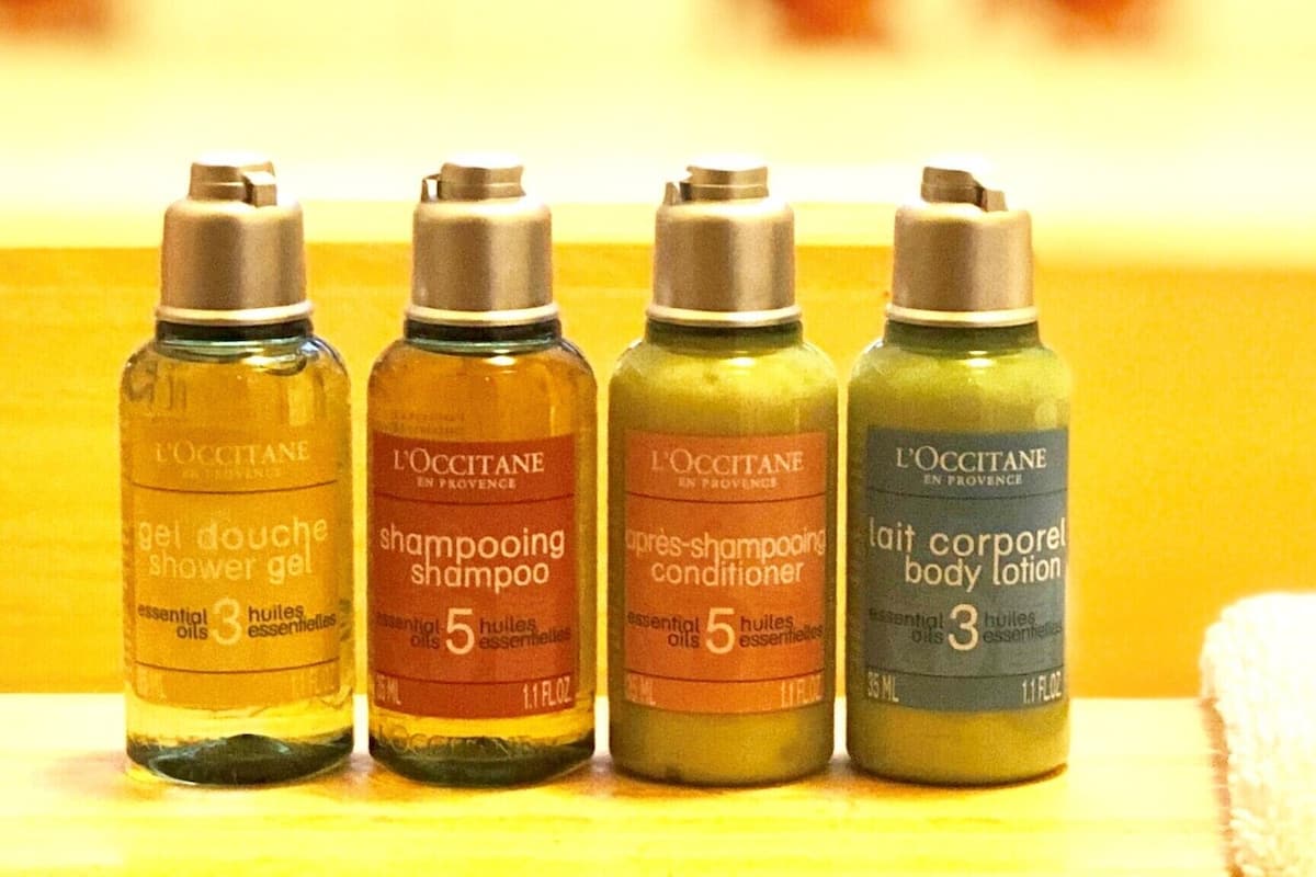 Four bottles of L'OCCITANE products on a shelf.