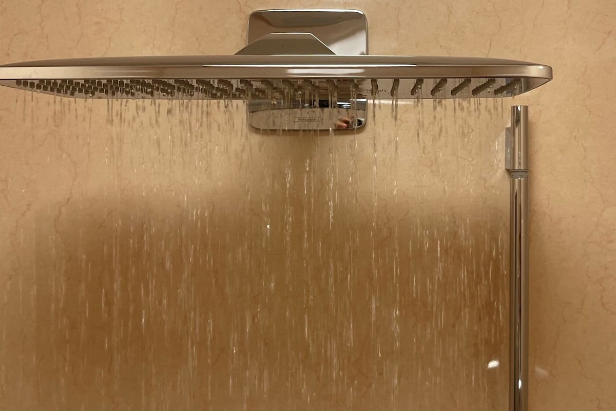 A shower with a rain-like water feature, a control panel, and a handheld showerhead.