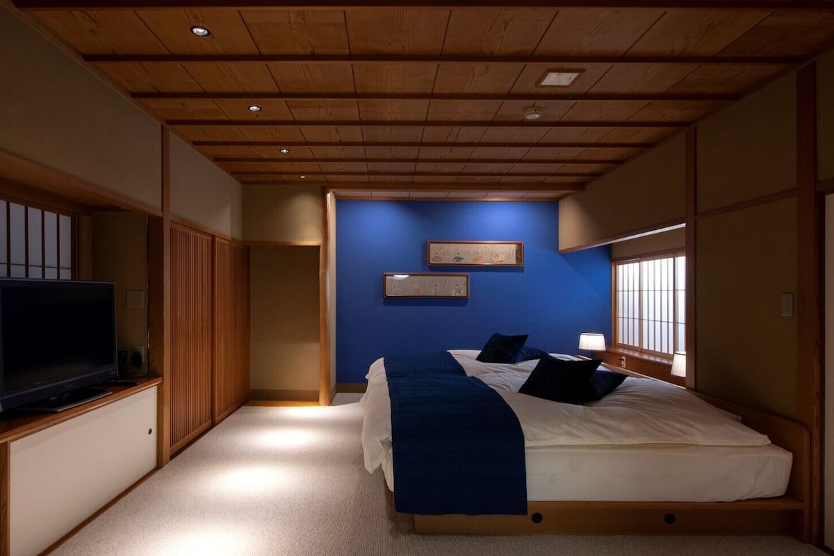A bedroom with a bed, a television, and a window.