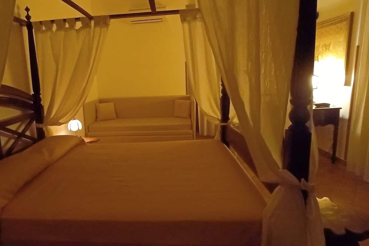 A bed with a canopy, a bedside table, and a lamp.