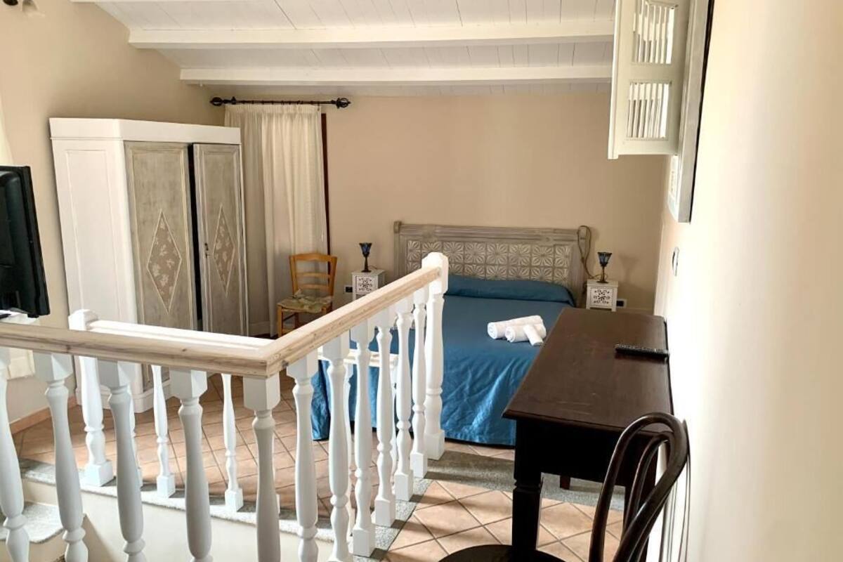 A bedroom with a bed, a wooden table, a chair, a wardrobe, and a staircase.