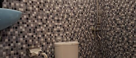 A bathroom with a toilet, a shower, and a sink.