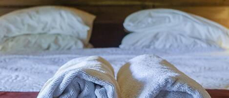 A neatly made bed with white linens and a painting of a landscape in the background.